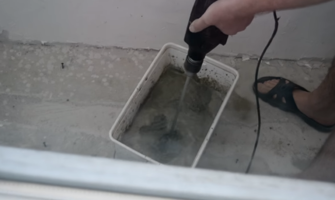 На фото показан процесс размешивания смеси для выравнивания пола под плитку