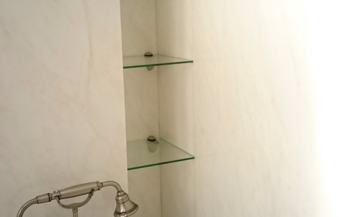 Полка, интегрированная в стену ванной.